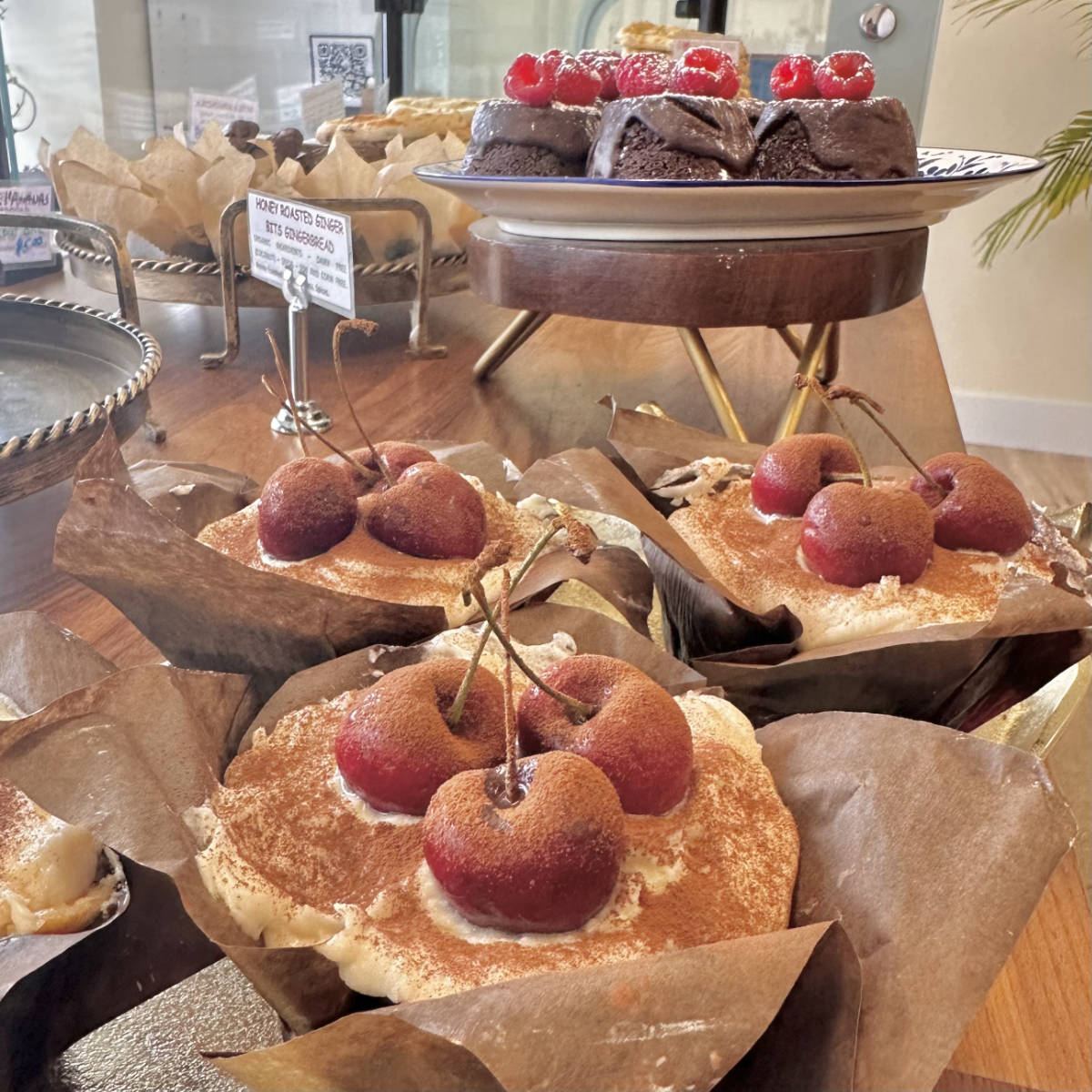 Cherry-topped pastries and chocolate cakes on the counter
